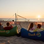 Teilnehmende chillen beim Sonnenuntergang am Strand im Beachvolleyball Camp auf Sylt