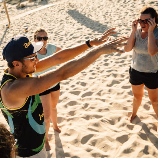 Beachvolleyball Trainer erklärt Teilnehmenden pritschen