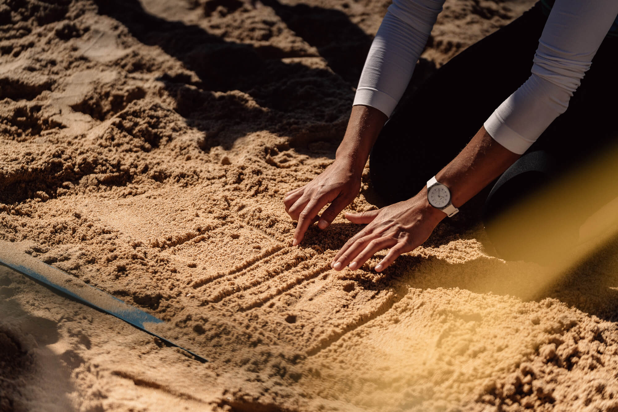 Trainerin malt Erklärung für Beachvolleyball in den Sand