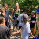 Teilnehmende machen Teambuildingübungen mit Traininer im Wald