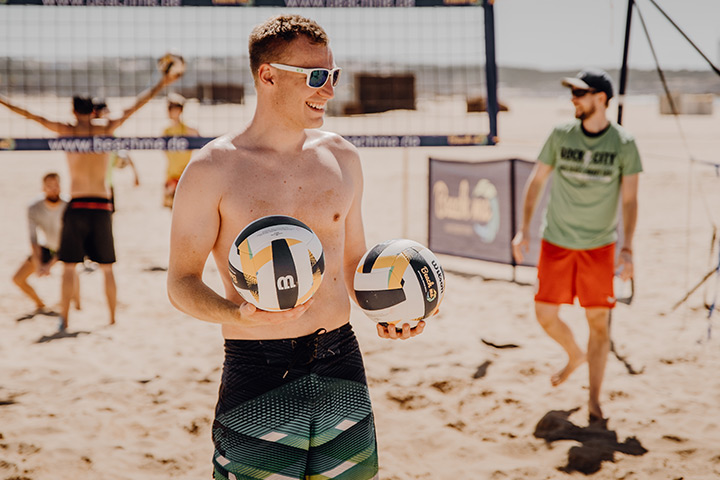 Participant practicing beach volleyball with two balls in hand