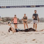 Trainerin liegt auf dem Boden und erklärt Trainingsgruppe Beachvolleyball