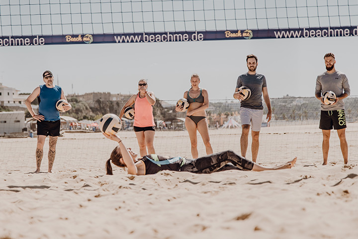 Trainer lies on the floor and explains training group beach volleyball
